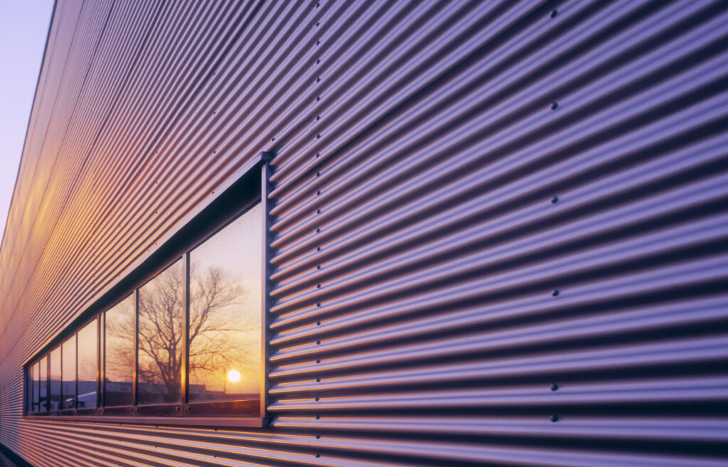 Sonnenuntergang spiegelt sich auf der Metallfassade eines neu errichteten Firmenlagers.